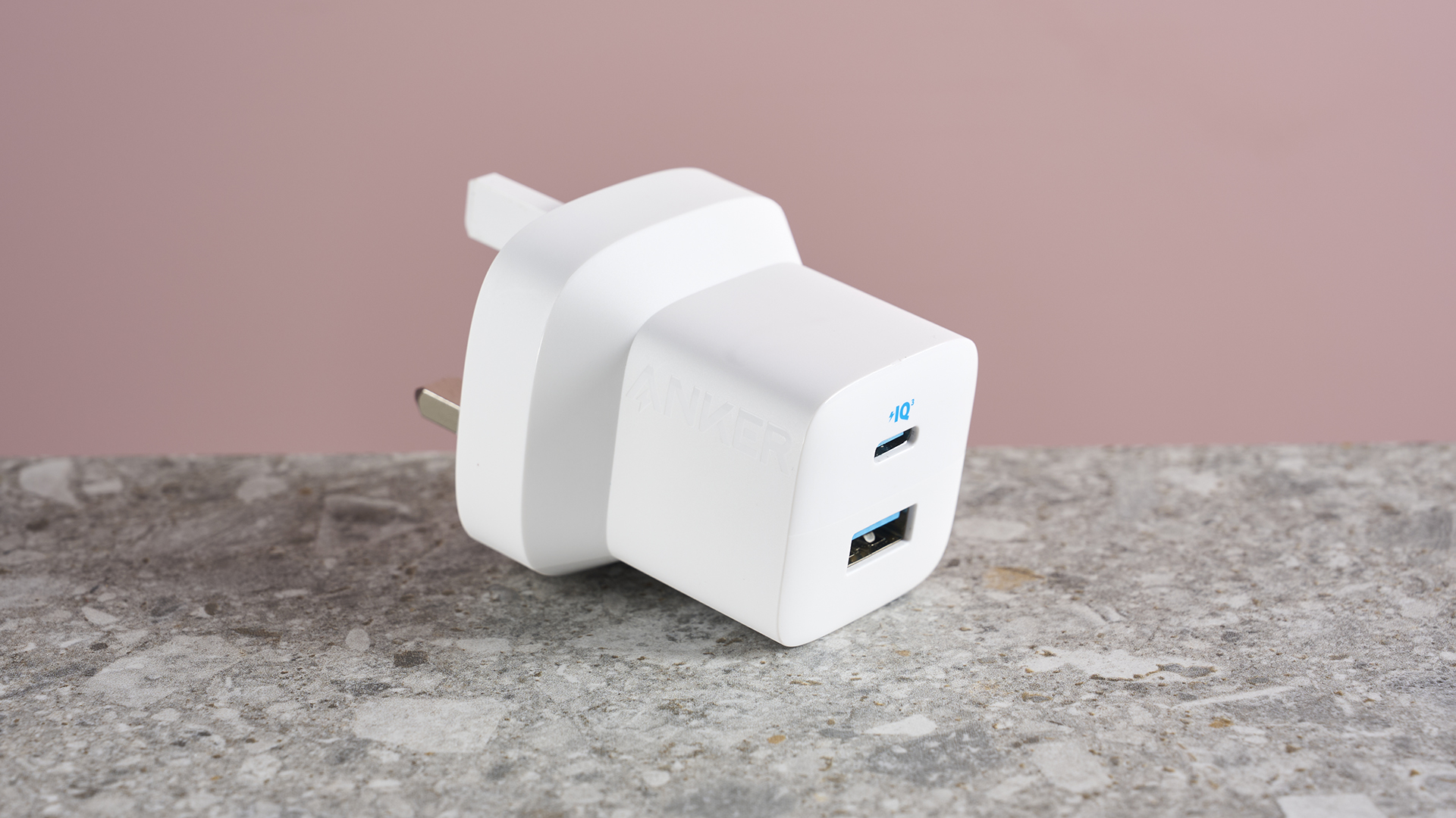 Anker 323 Charger (33W) sat on stone surface with prongs folded outwards