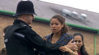Gugu Mbatha-Raw being held back by a cop in Doctor Who.