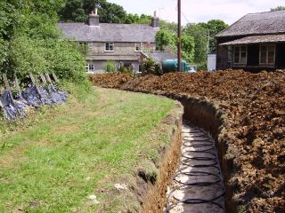 Installing a ground source heat pump ground array in slinkie trenches