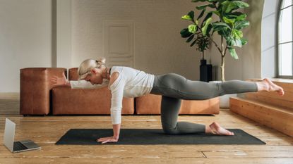woman does bird dog exercise at home