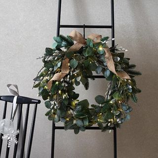 Natural christmas wreath with ribbons on ladder