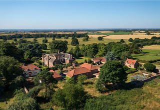 Birds eye view shot of a large estate with a big house and multiple outbuildings