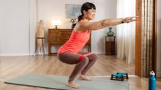 Woman doing resistance band leg workout on yoga mat in living room 