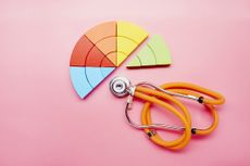 High angle view of a pie chart made of colorful building blocks and orange stethoscope 