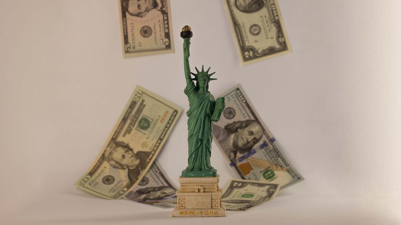 Statue of Liberty figurine with money falling down on it