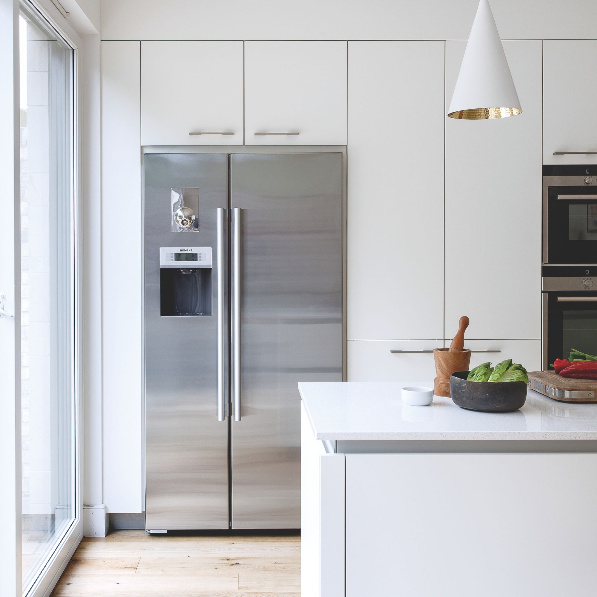 White kitchen with white cabinets and a large silver fridge-freezer 