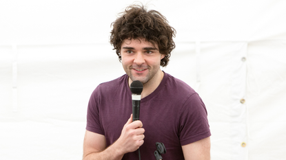 Edd Hedges on stage with a microphone