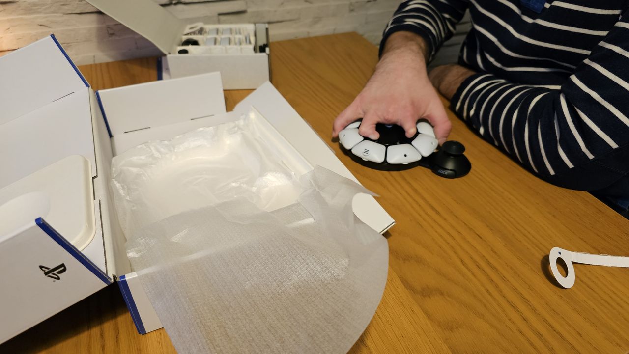 Unboxing the PlayStation Access controller with one hand on a wooden surface