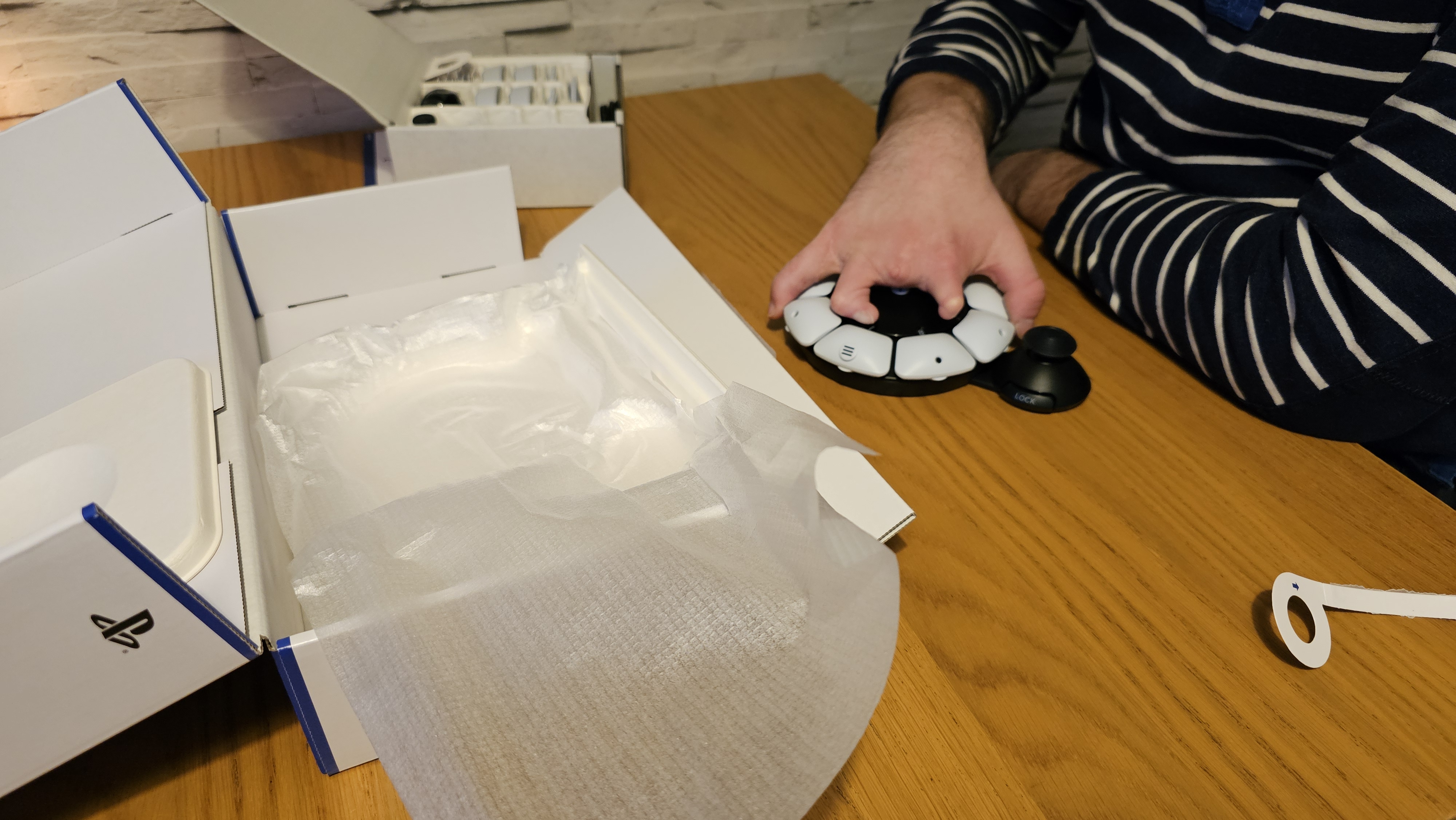 Unboxing the PlayStation Access controller with one hand on a wooden surface