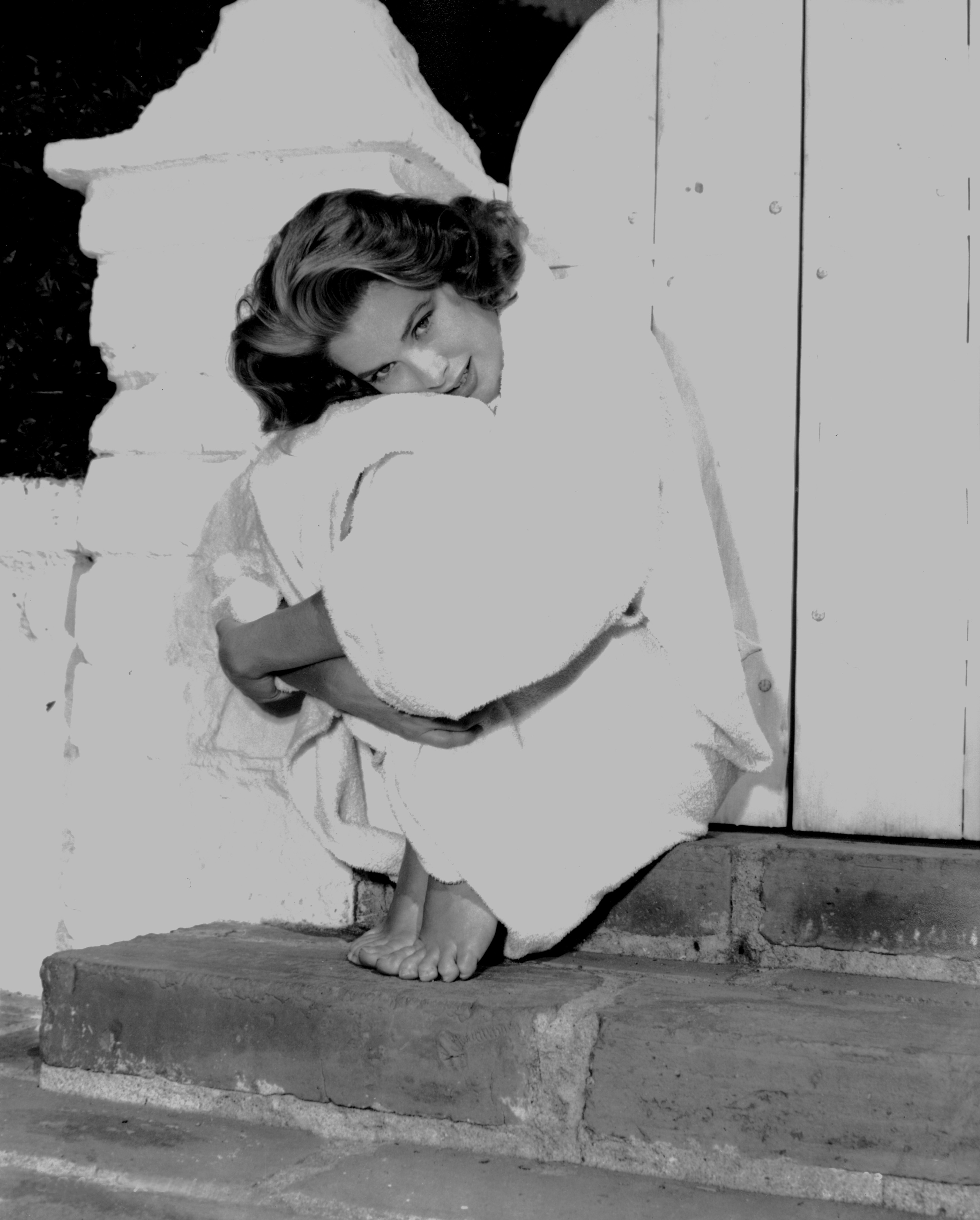 Grace Kelly sits on a step wearing a white outfit with her hair cut into a bob