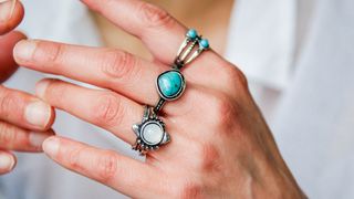 close up on a woman's hand with three silver-colored rings on her middle three fingers