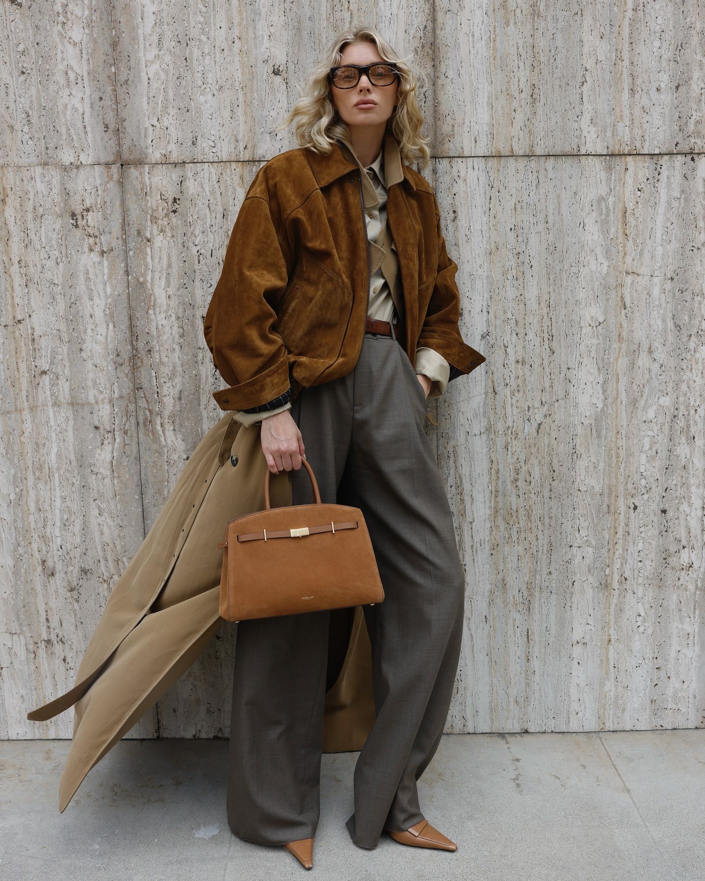 An image of @hoskelsa wearing tailored trousers, trench coat, pointed-toe heels and a suede jacket.
