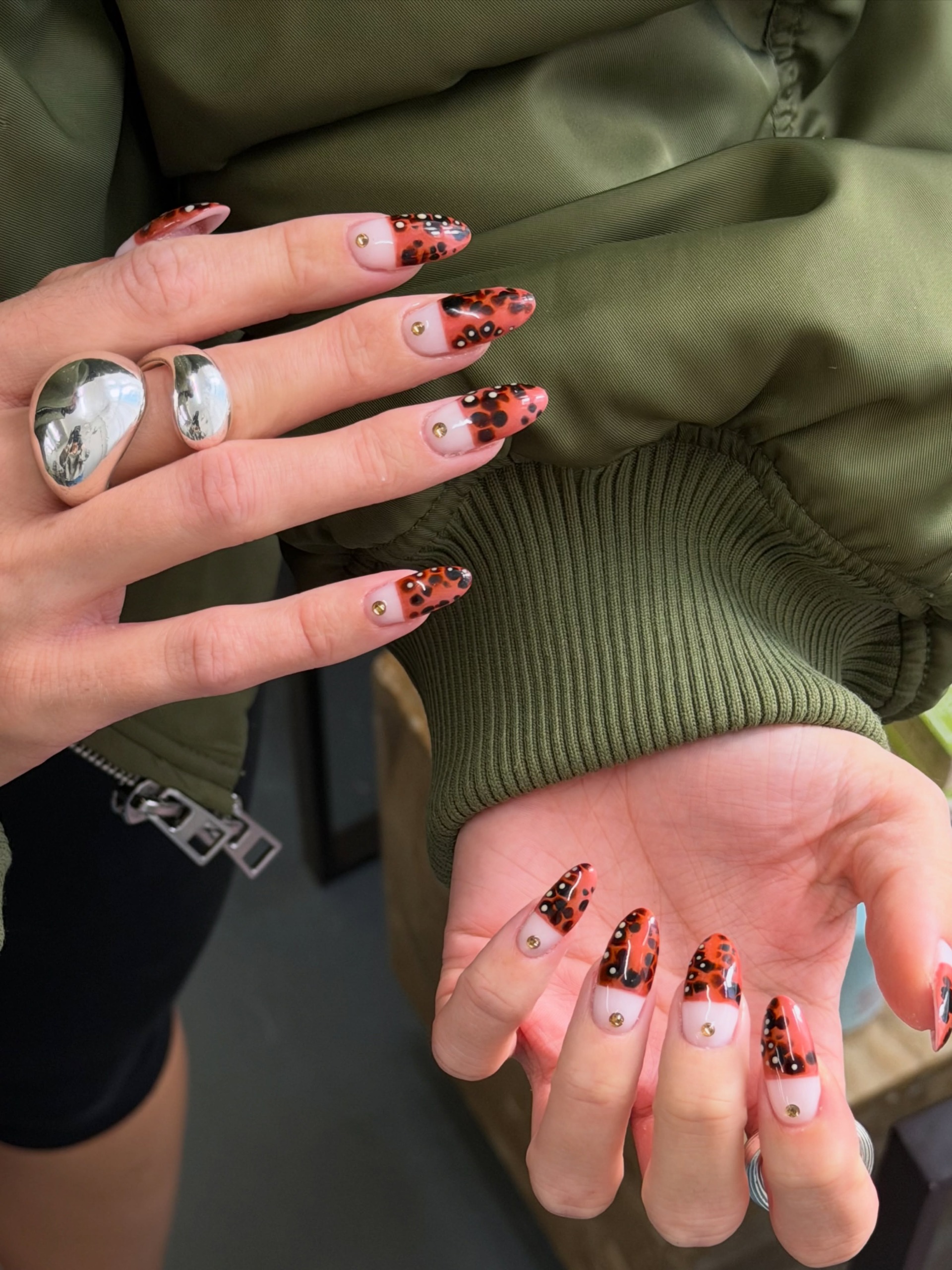 pink-based nails with mixed animal-print French tips against an olive green outfit