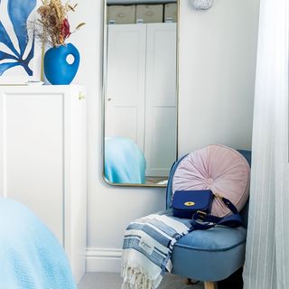 blue and white bedroom with blue chair and mirror