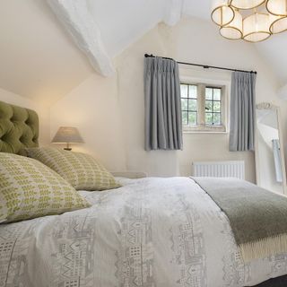 Cotswold cottage's grey and white bedroom, with yellow cushions and victorian mirror