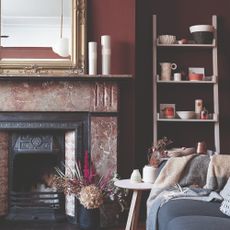 A living room with a marble fireplace painted in a dark chocolate brown shade