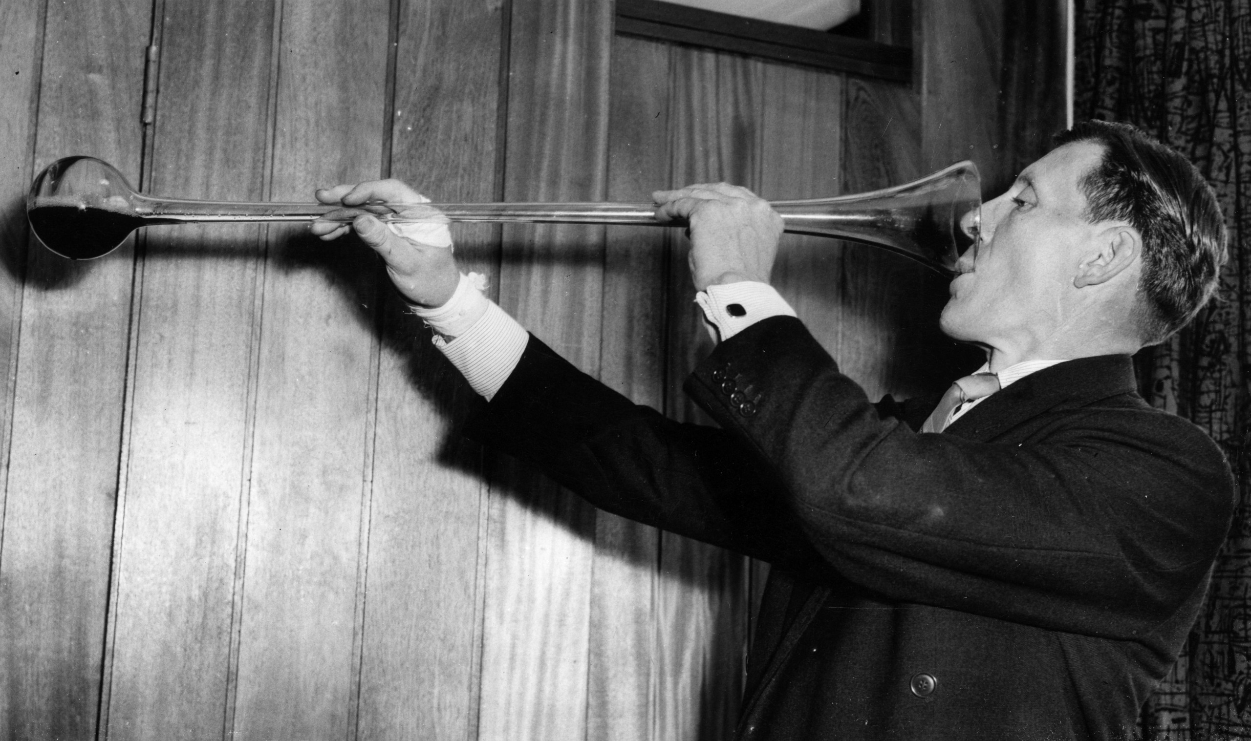 A man takes on a yard of ale in a black and white photograph