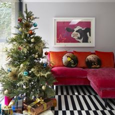 Living room with real Christmas tree and pink sofa.