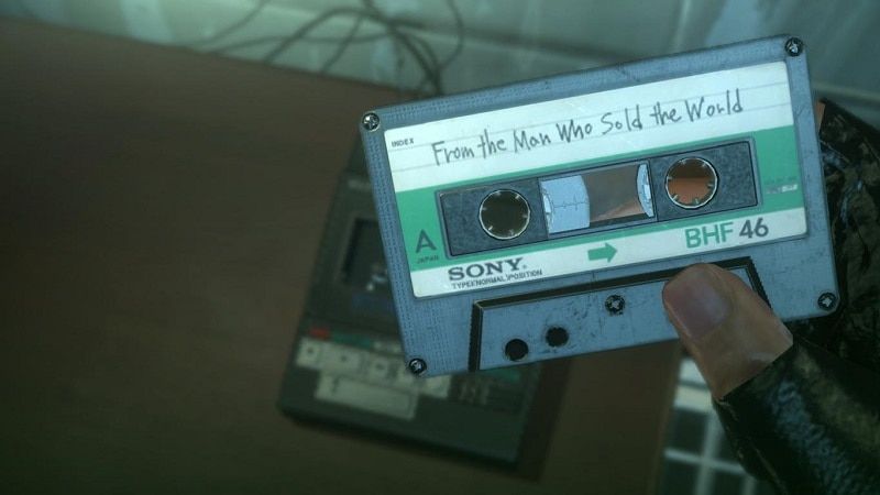 Venom Snake looks at a cassette tape.