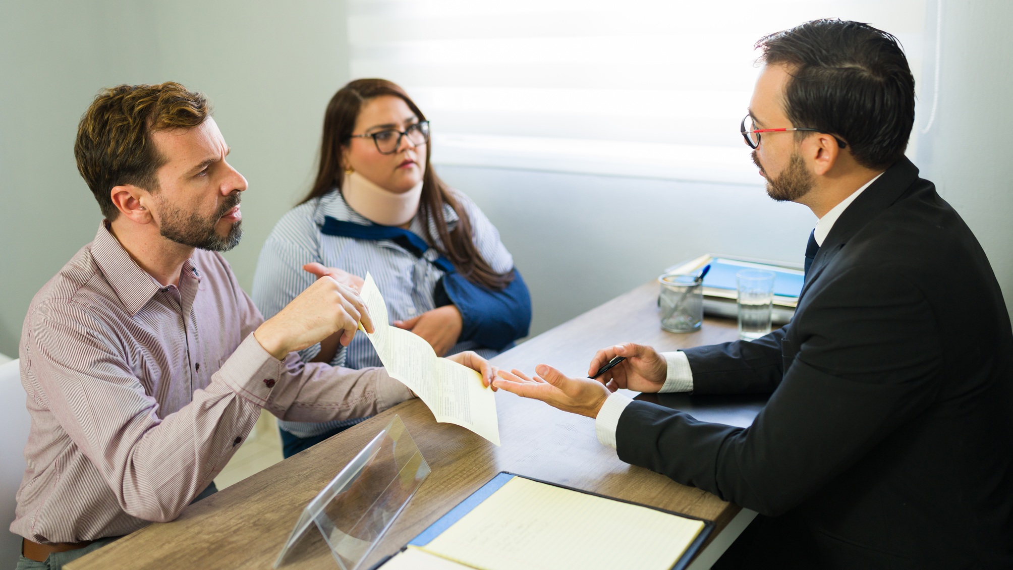 A man and an injured woman discuss their case with a lawyer. 
