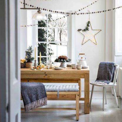 Wooden dining table and bench in dining room with white walls green and grey décor 