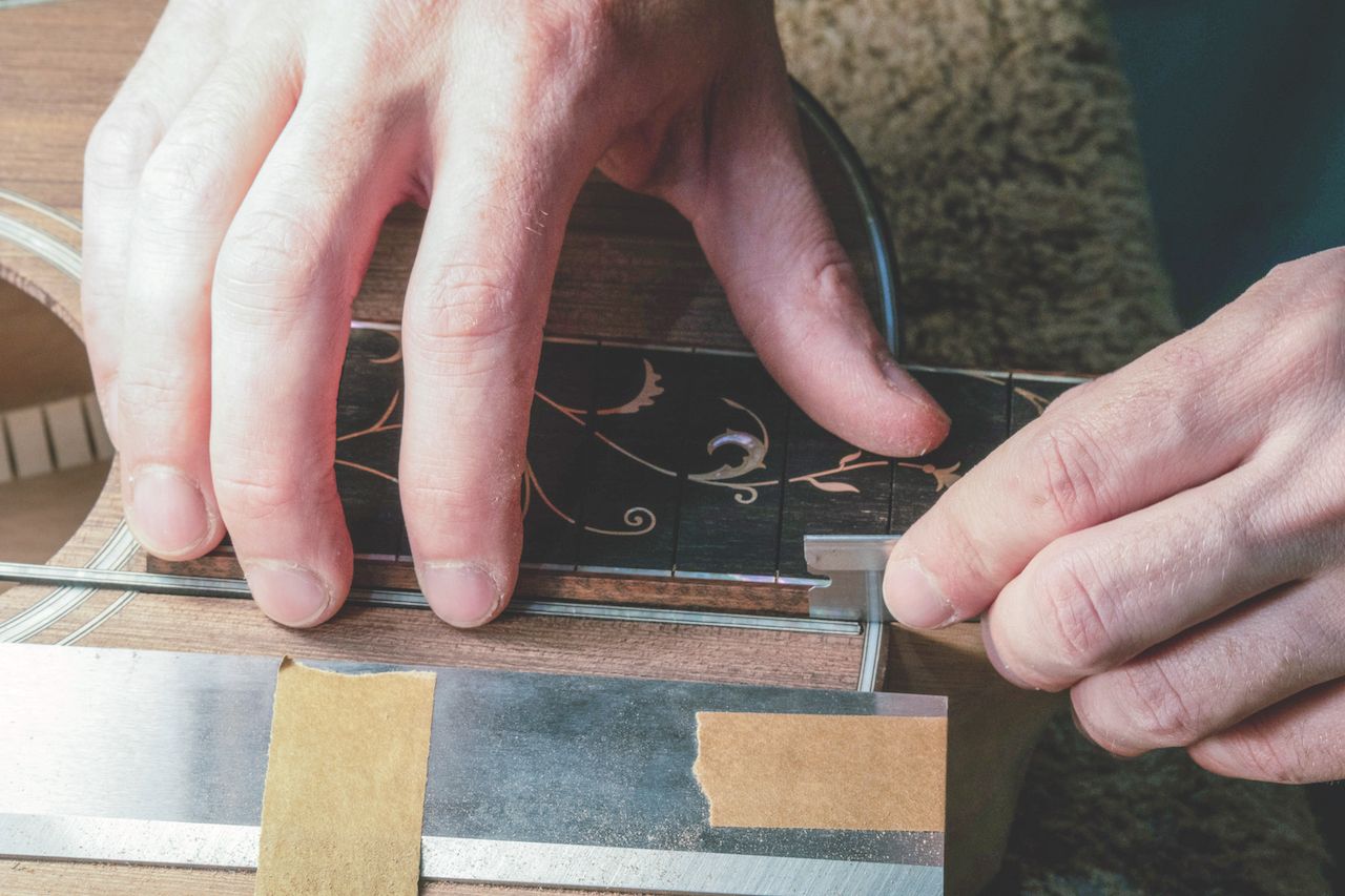 An artisan works on a 45-style fingerboard extension with gold awabi shell inlay and 14k gold purfling. The fingerboard is destined to be used in the making of an H13 1854, a quintessentially Santa Cruz custom H13 model.