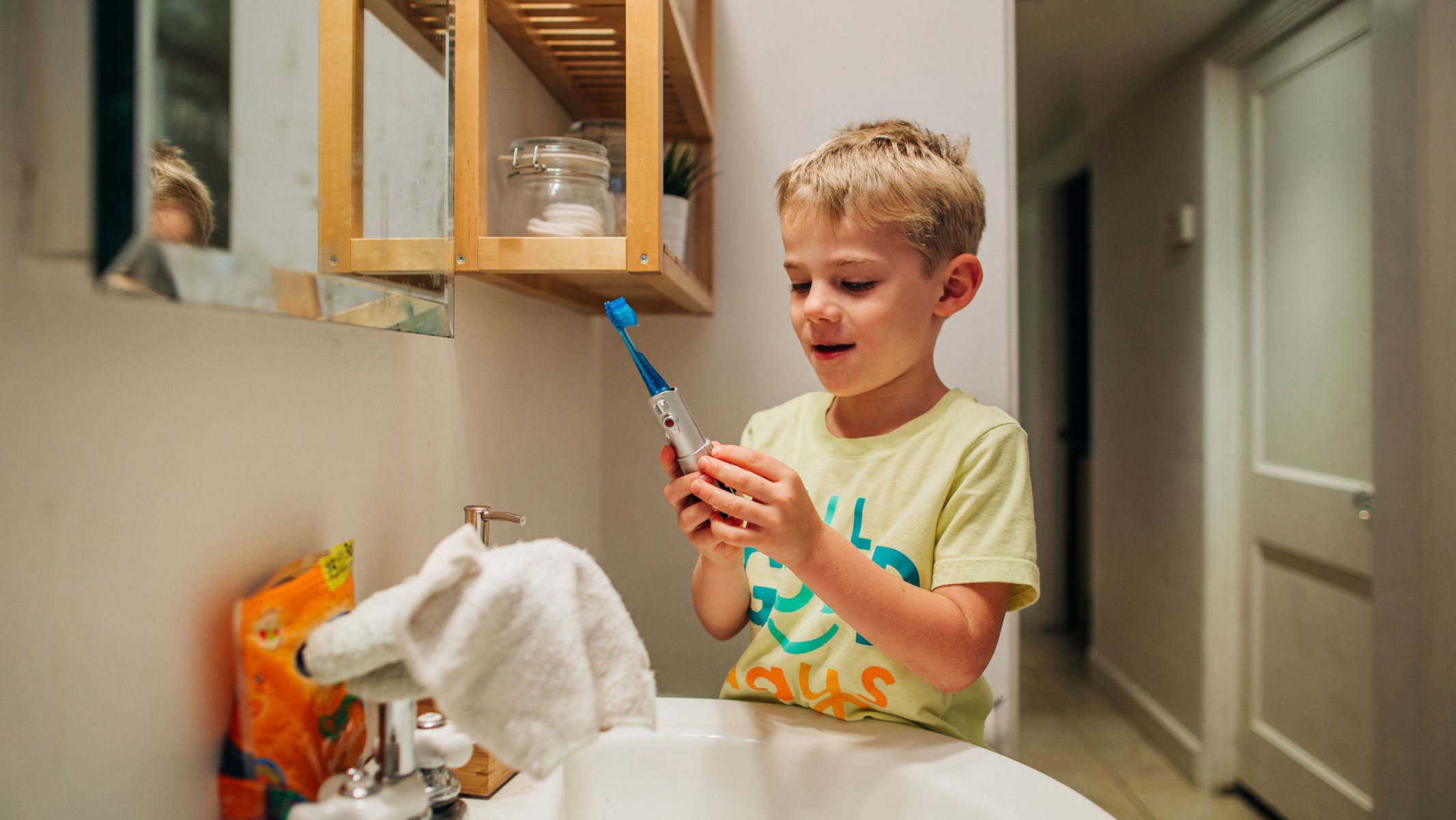 A picture of a young boy playing with the settings of his electric toothbrush