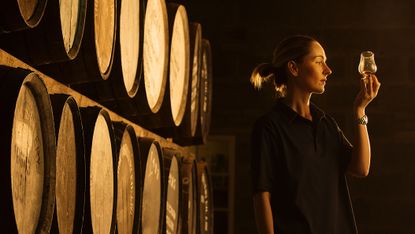 A woman tasting whisky in a cellar