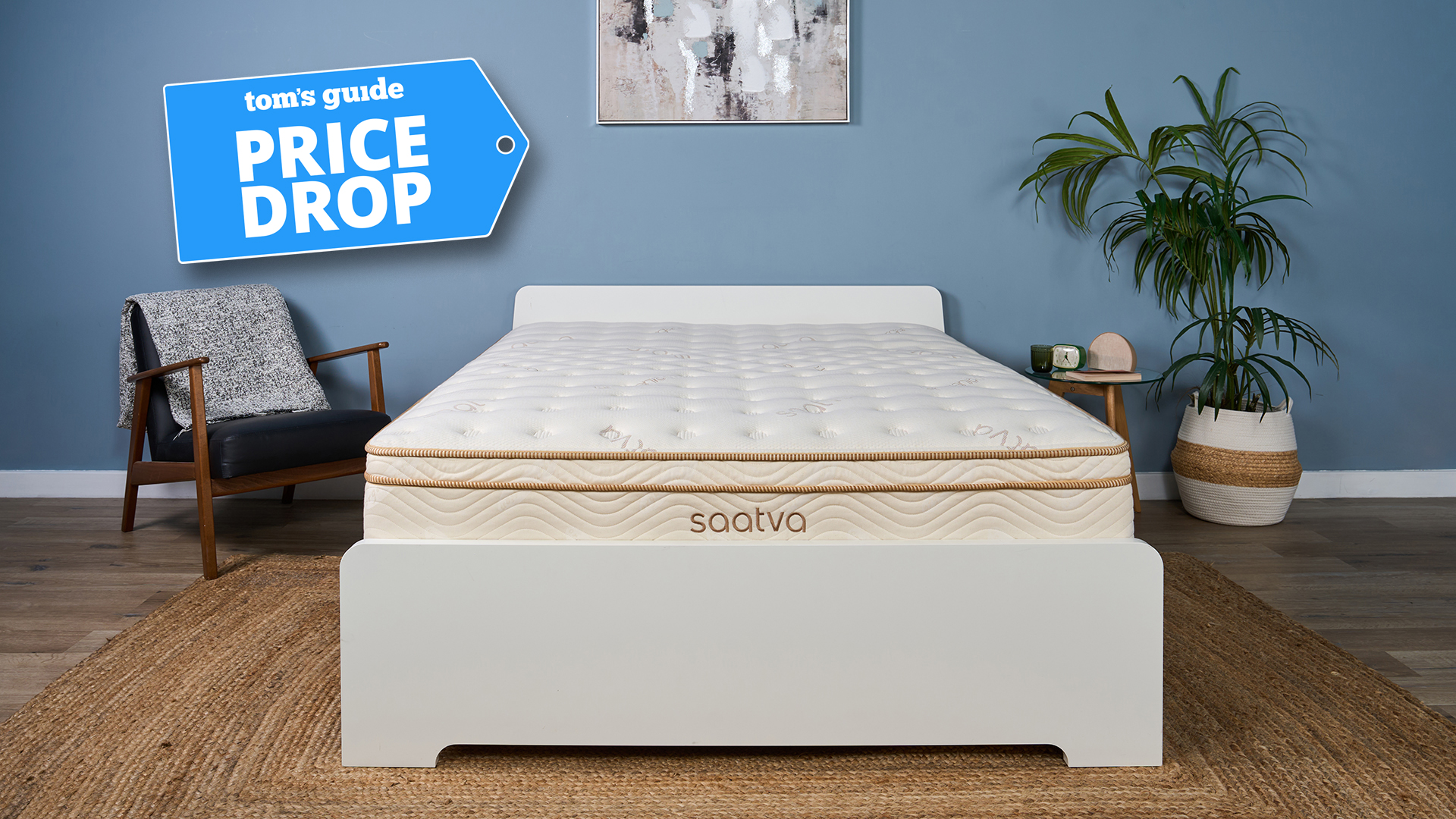 The Saatva Classic Mattress on a bed frame in our Sleep Lab, decorated like a bedroom. In the top left corner is a Tom's Guide Price Drop badge