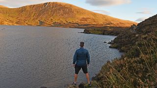 Hiker wearing Kathmandu Heli R Down Jacket at Loch Skeen