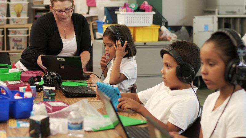 Kids use headphones and laptop computers in the classroom