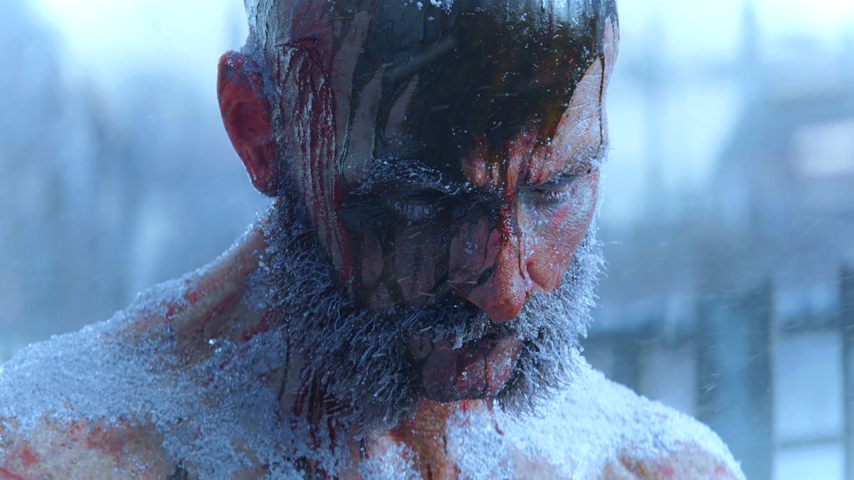 Frostpunk 2 reveal trailer screenshot showing a middle-aged man with short hair and thick facial hair sitting as a snowy storm rages on, blood streaming down his face