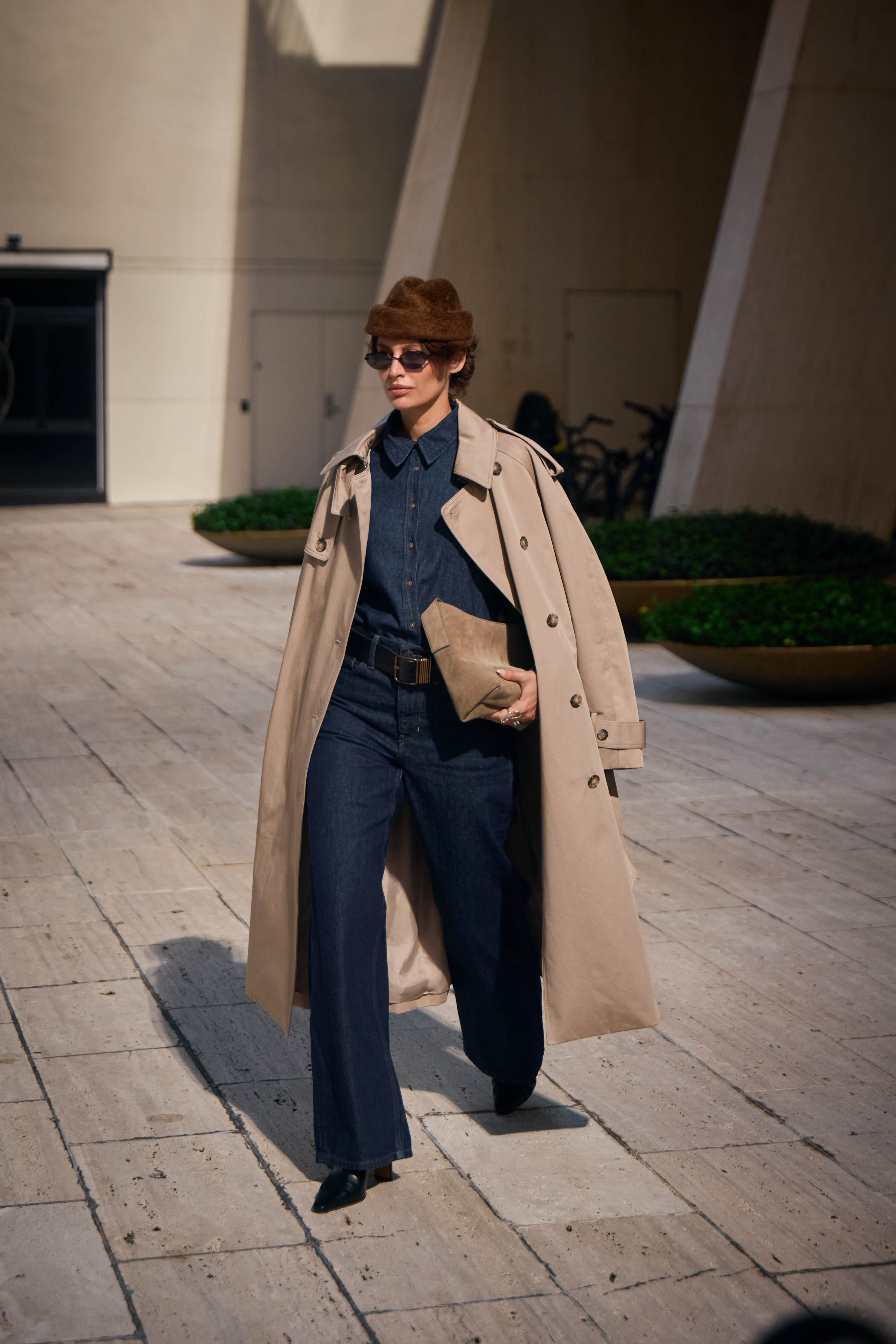 A person in double-denim with pointed-toe boots and a trench coat.