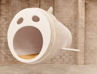 A white hanging sculpture by Porky Hefer representing a sea animal shaped like a takeaway coffee cup