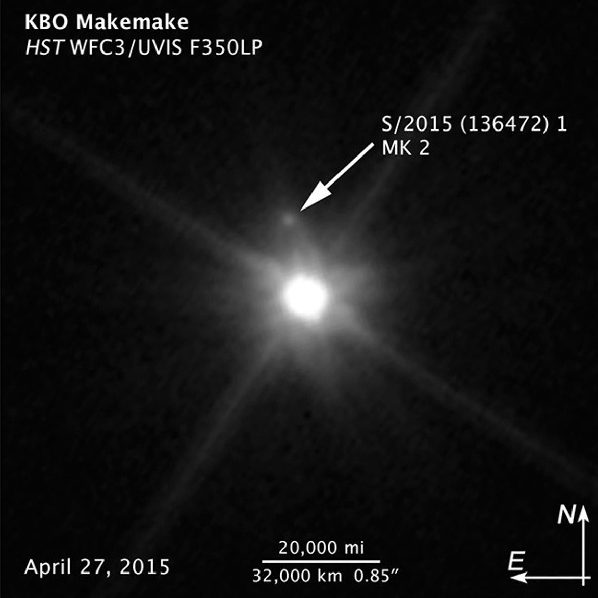 A photo of Makemake as a blurry point of light with arrows pointing to the location of its moon