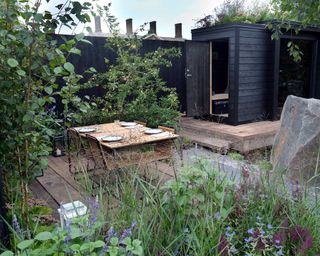 modern garden with decking, shed, dining set and boulder