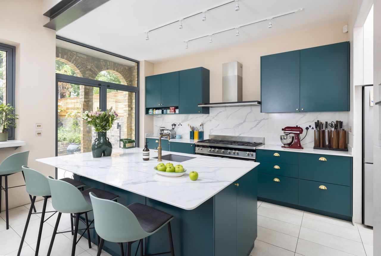 A modern kitchen extension with blue bespoke fittings and marble worktops