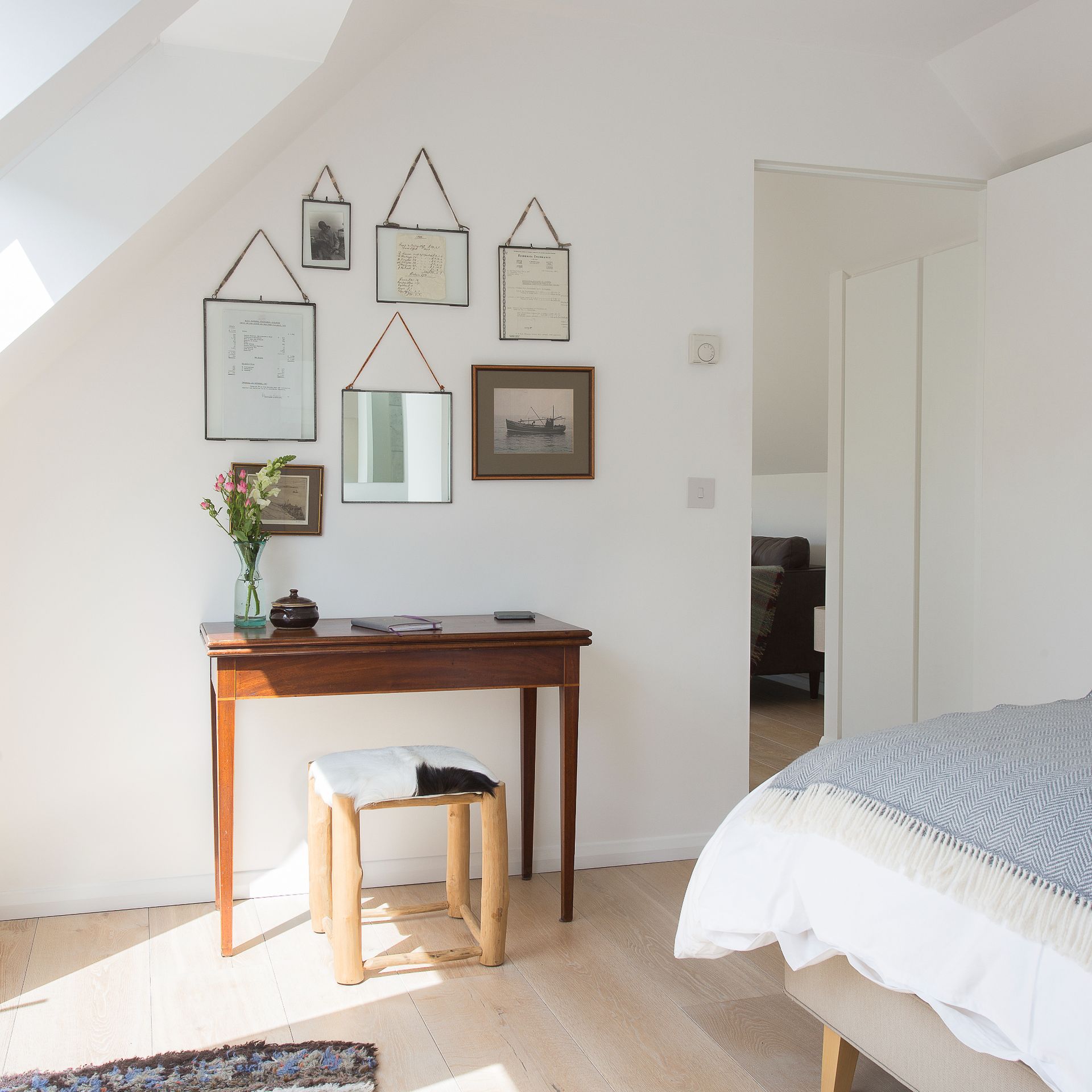 White bedroom with wooden floor and hung frames