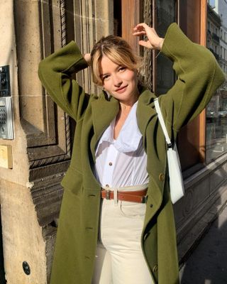 Sabina Socol wearing French girl autumn beauty trend curtain bangs with an olive green trench coat