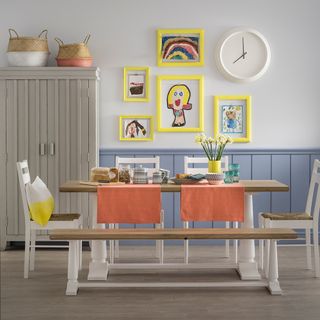dining area with white wall and wall clock and wooden floor and dining table and wardrobe and painting frame
