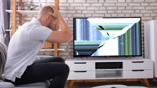 Distraught man sat in front of a broken TV