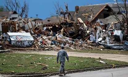 A soldier walks past the wreckage left by a deadly tornado that moved through Moore, Okla., May 21.