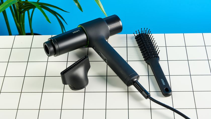 the heist 3.0 men&#039;s hair dryer in black with a bright green ring and magnetic attachment photographed against a blue background 