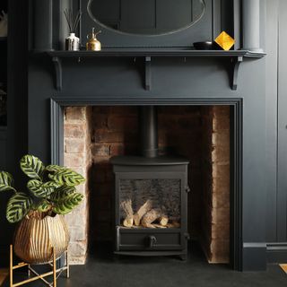 A brick fireplace with a black-painted surround and mantel, fitted with a wood-burning stove