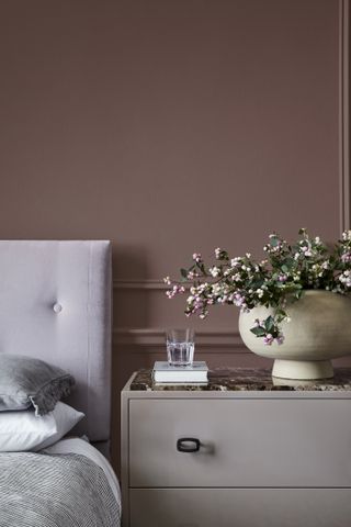 A purple bed headboard against dusty pink walls