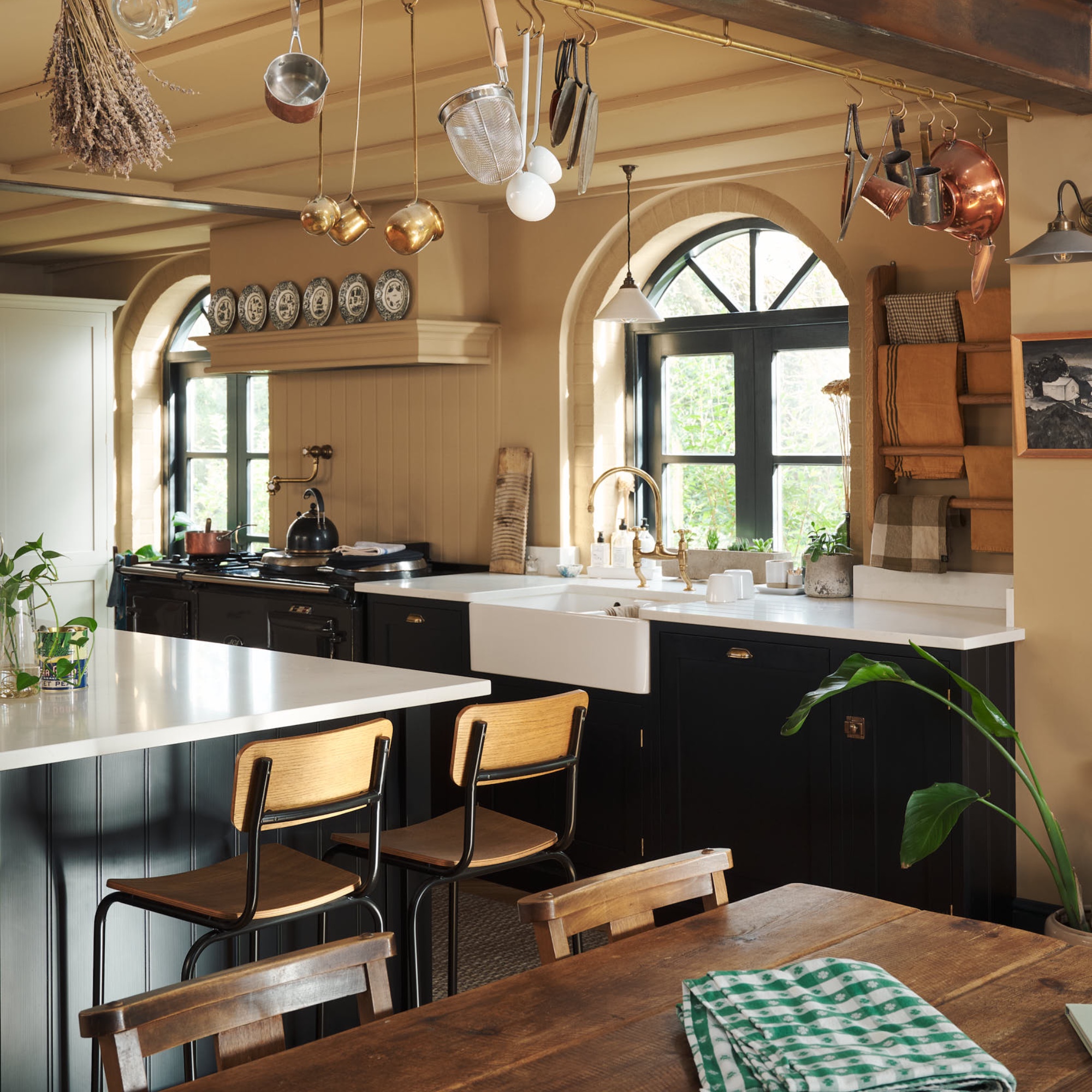 black and ochre kitchen with white worktops, tongue and groove walls, bar stools, dining table