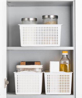 An image of gray wooden shelves with white plastic baskets holding kitchen essentials