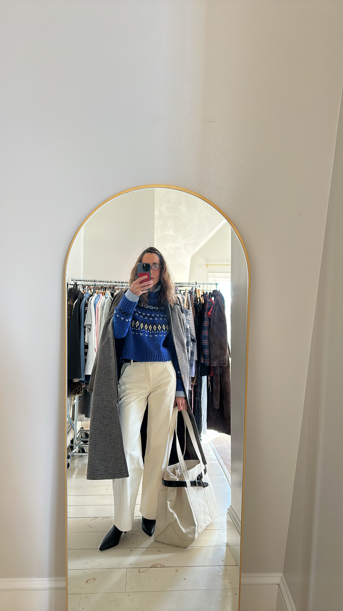 Larissa Mills wearing white jeans, a blue Fair Isle sweater, and a gray coat