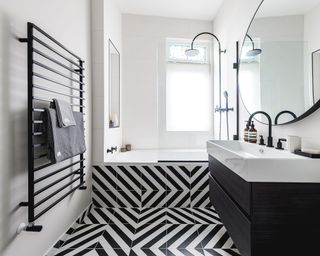 Black and white floor tiles laid up the side of the bath with black sanitary ware