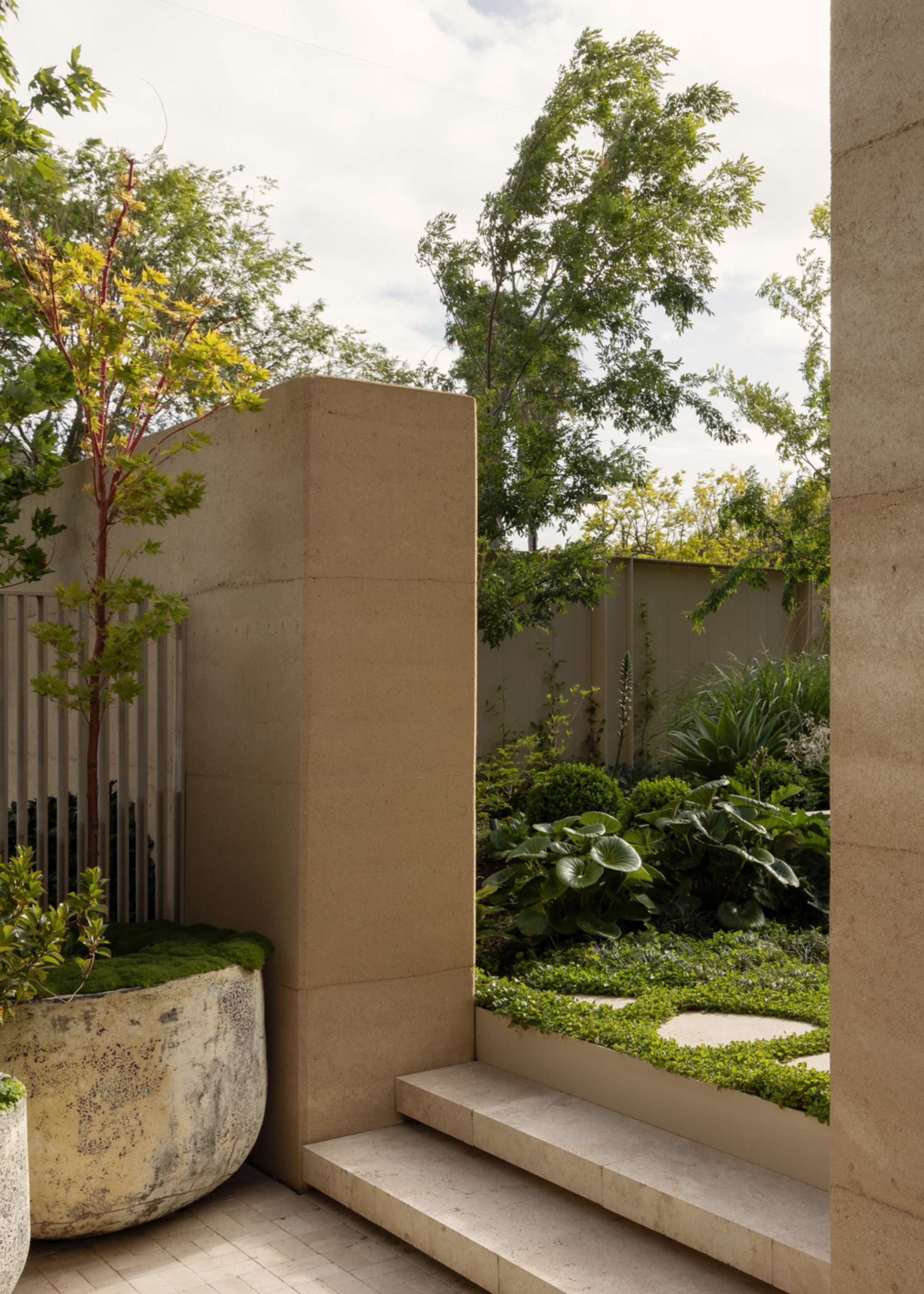 An outdoor space with beige landscaping leading up to a moss garden
